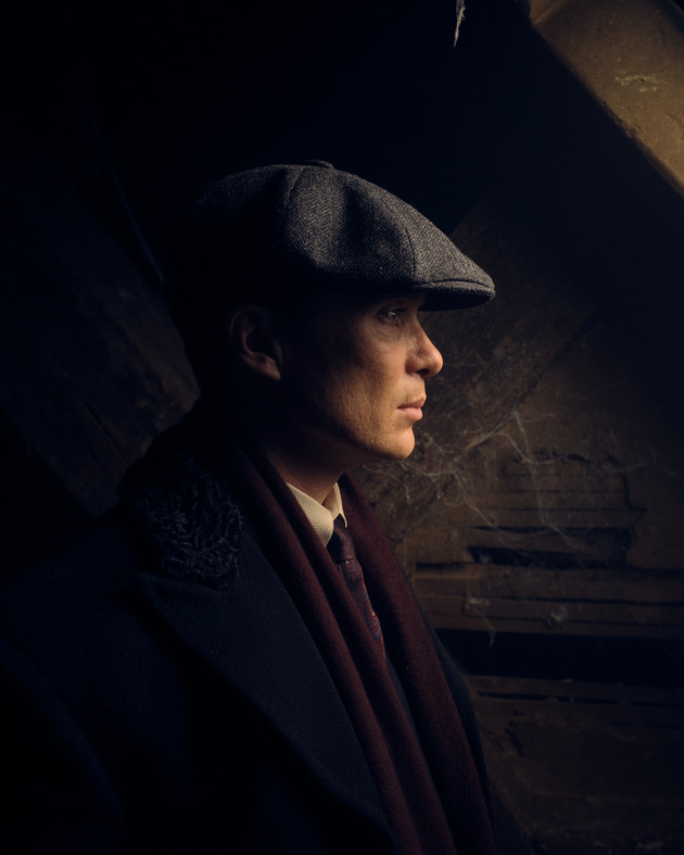 Cillian Murphy, as Thomas Shelby in Peaky Blinders, in front of a wooden wall.