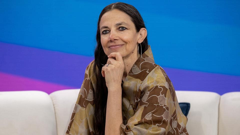 Justine Bateman brings a hand to her chin and smiles softly on the couch on the TODAY show