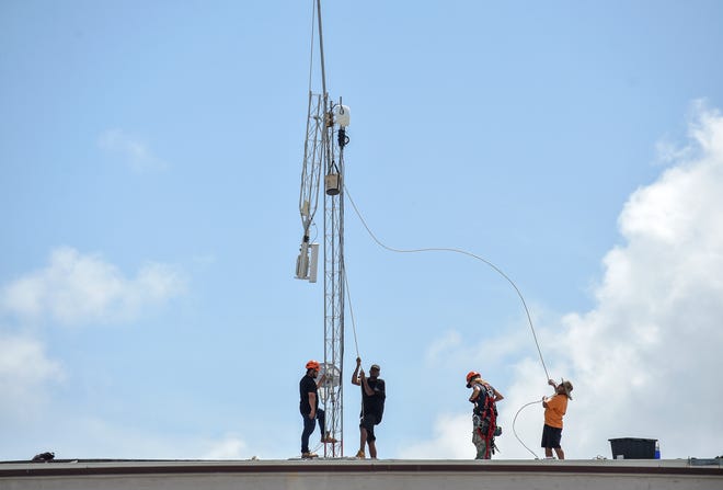 A crew from Internet service provider Florida Broadband works to remove an access tower from the roof of the Theater Plaza building on 14th Avenue in Vero Beach, Florida on Saturday, August 31, 2019, in preparation for the possible arrival of Hurricane Dorian.